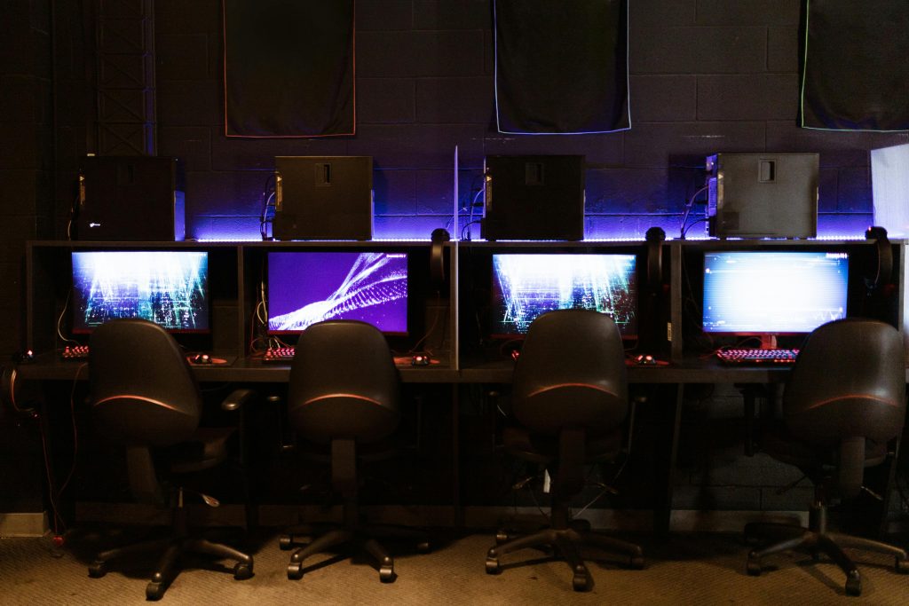 A modern gaming setup with multiple computers and LED lighting, perfect for e-sports and gaming environments.